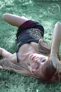 shooting glamour en extérieur. Karen allongée sur l'herbe avec une mini robe noire. séance photo avec Fabien Ferrère photographe de mode et de portrait à Pau et 64